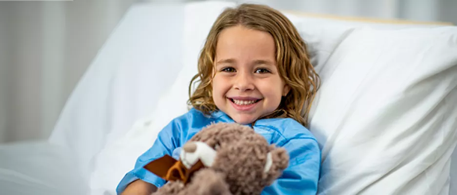 A smiling child laying in bed