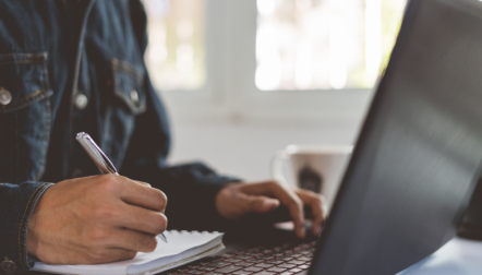 person on computer taking notes