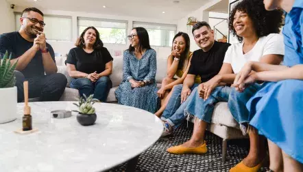 A diverse group of friends sitting around a living room table