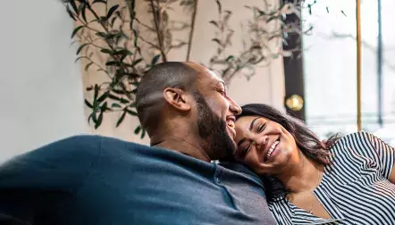Black couple hugging on sofa