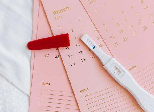 Pregnancy test on top of pink calendars