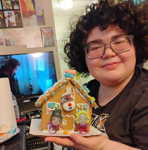 Jaelynn holding up their decorated gingerbread house 