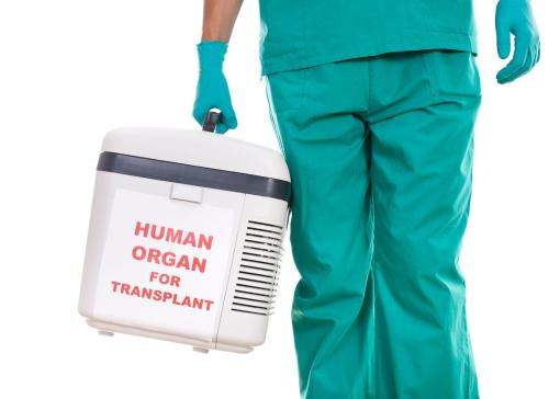 Person in green scrubs carrying a cooler with Human Organ for Transplant written on it