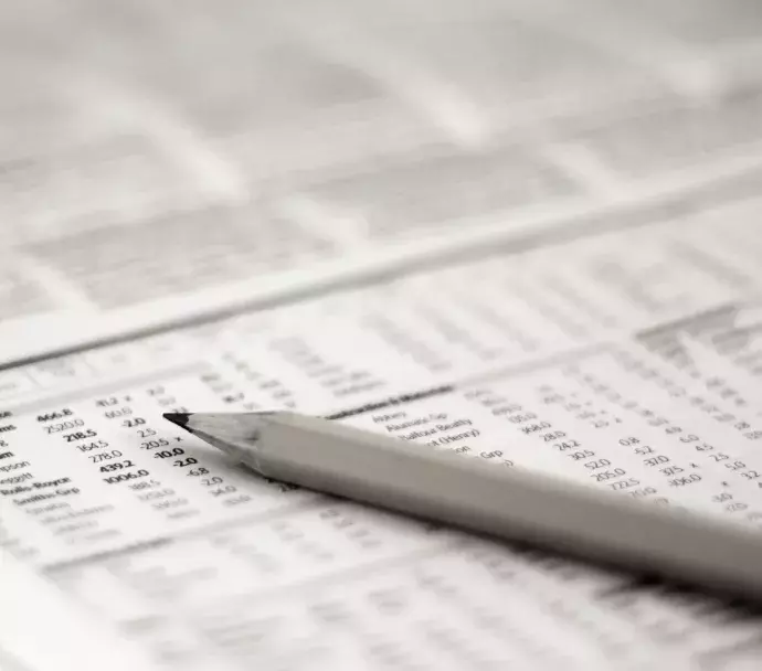 Stocks section of newspaper with pencil on top