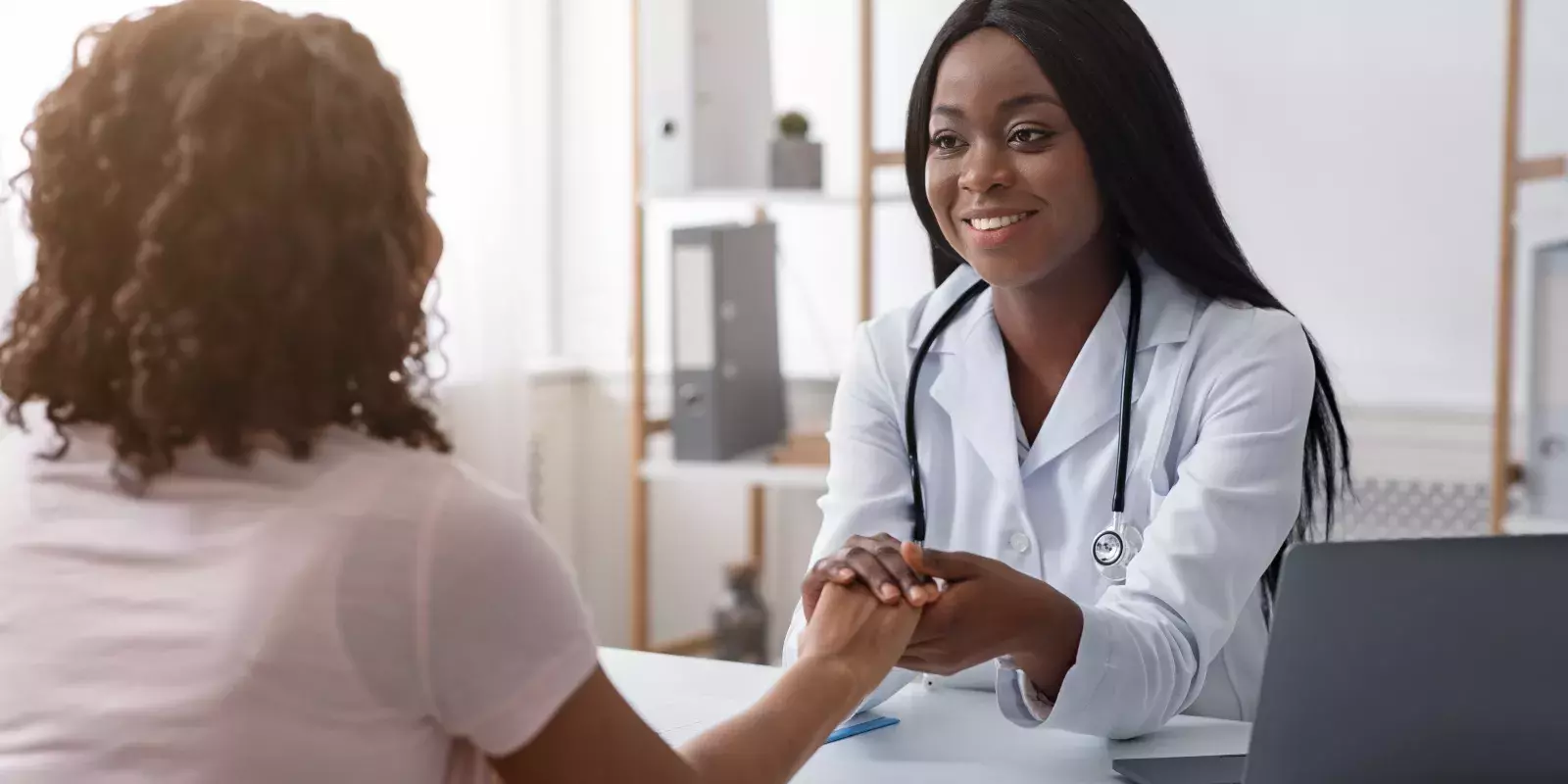 Female doctor holding a patients hand